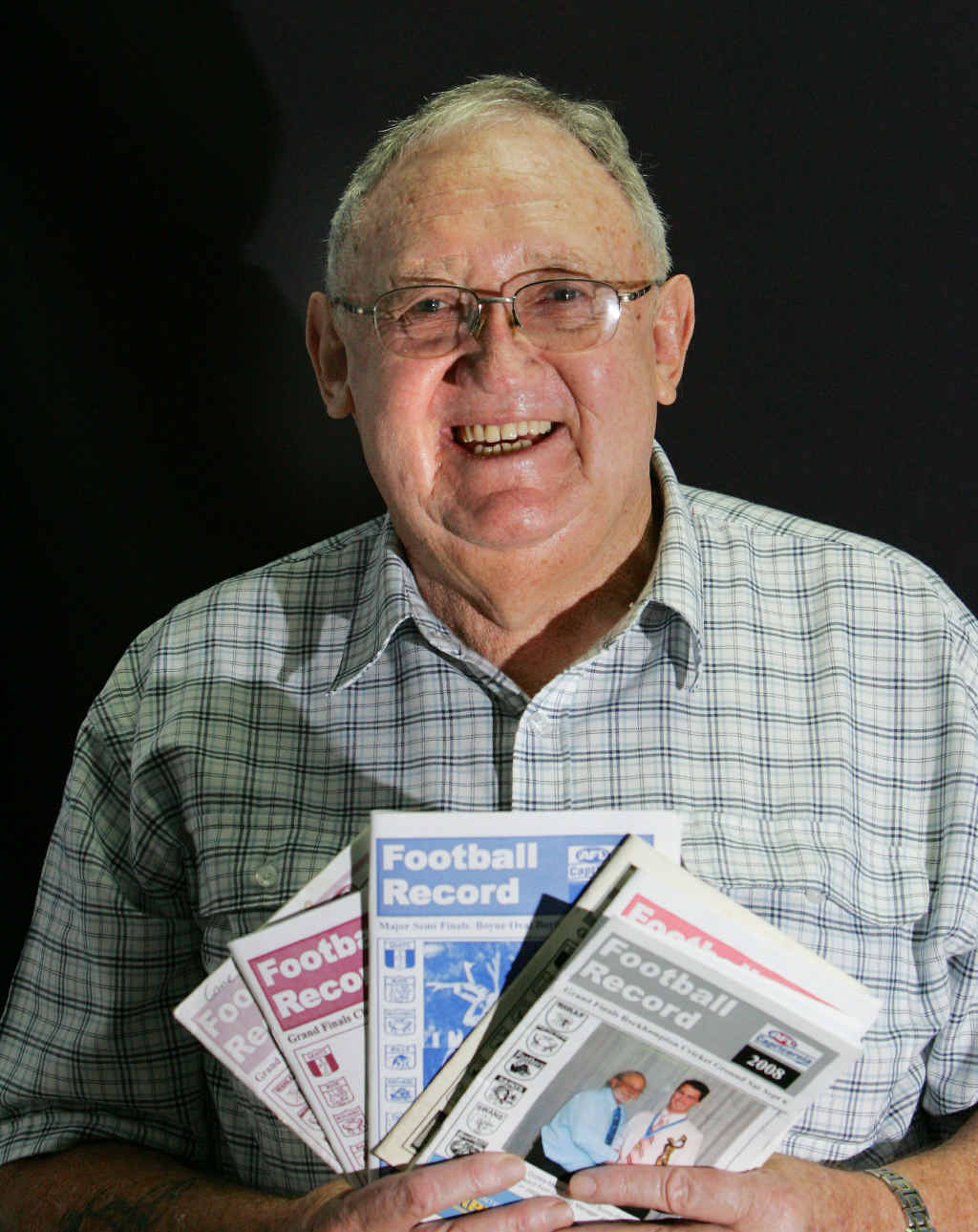 REST EASY: Rockhampton’s John Broad holding a series of AFL Capricornia record books. John passed away last Wednesday.