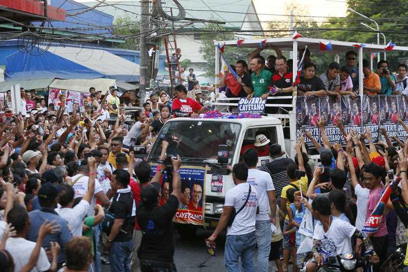 Presidential candidate Mayor Rodrigo Duterte, top left, is greeted by supporters as his campaign motorcade makes its way through the streets of Malabon Wednesday, April 27, 2016 north of Manila, Philippines. The tough-talking Duterte, the mayor of the southern Philippine city of Davao, is the front-running candidate leading to the May 9 presidential elections. Presidential candidate Mayor Rodrigo Duterte, top left, is greeted by supporters as his campaign motorcade makes its way through the streets of Malabon Wednesday, April 27, 2016 north of Manila, Philippines. The tough-talking Duterte, the mayor of the southern Philippine city of Davao, is the front-running candidate leading to the May 9 presidential elections.