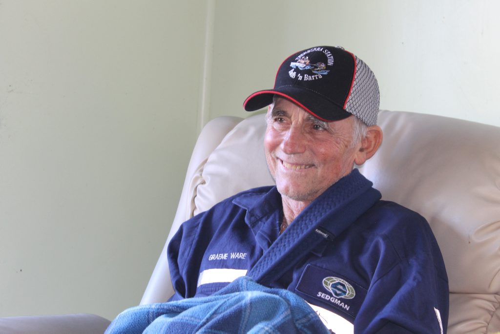 STILL SMILING: Pinnacle cattle farmer Graeme Ware, 66, listens in as a colourful poem by his mate David Oliver about his recent run-in with a wild bull is recited to him. STILL SMILING: Pinnacle cattle farmer Graeme Ware, 66, listens in as a colourful poem by his mate David Oliver about his recent run-in with a wild bull is recited to him.