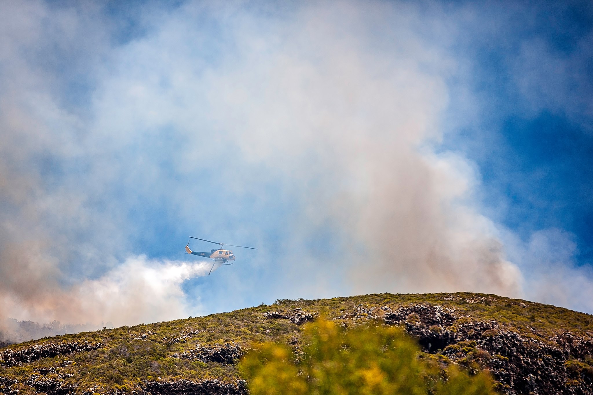 Helicopters water bomb a blaze burning on Mount Coolum. Helicopters water bomb a blaze burning on Mount Coolum.