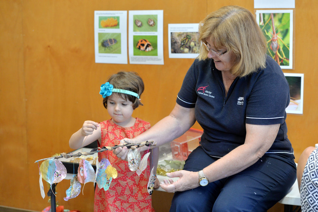 Mackay Regional Botanical Gardens visitor services officer Maya Harrison helps Asher Brodie with her decorations.