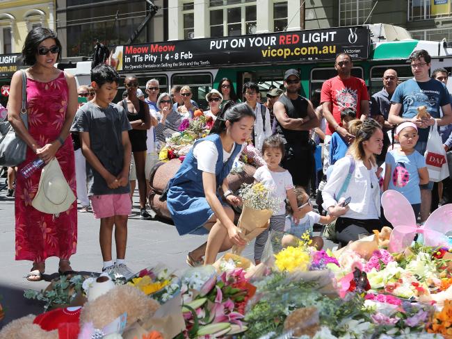 Visitors lay flowers at a shrine on Bourke St.